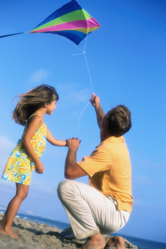 Father and daughter flying a kite together on the beach